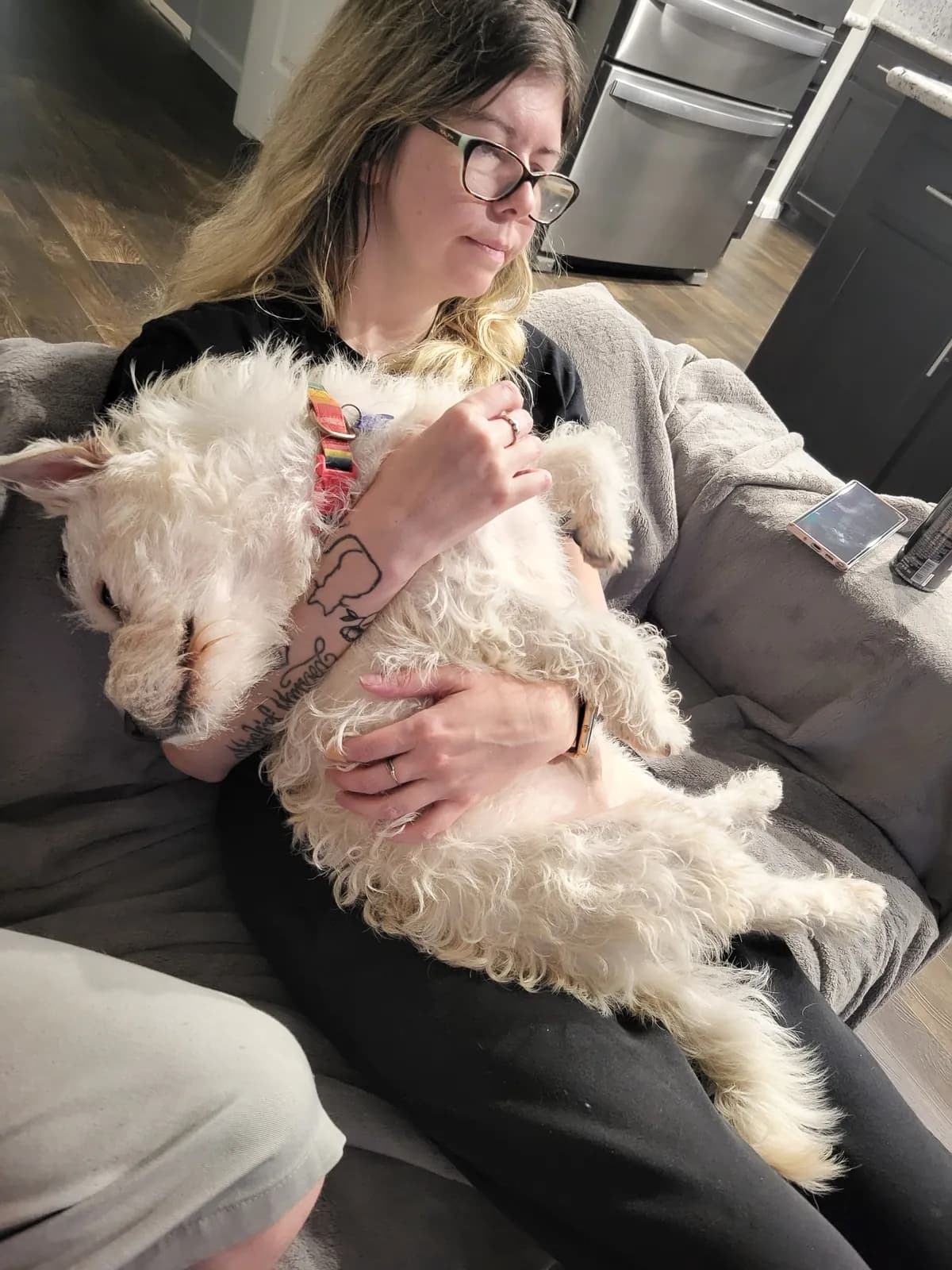 Sarah cuddling a fluffy white dog on the couch